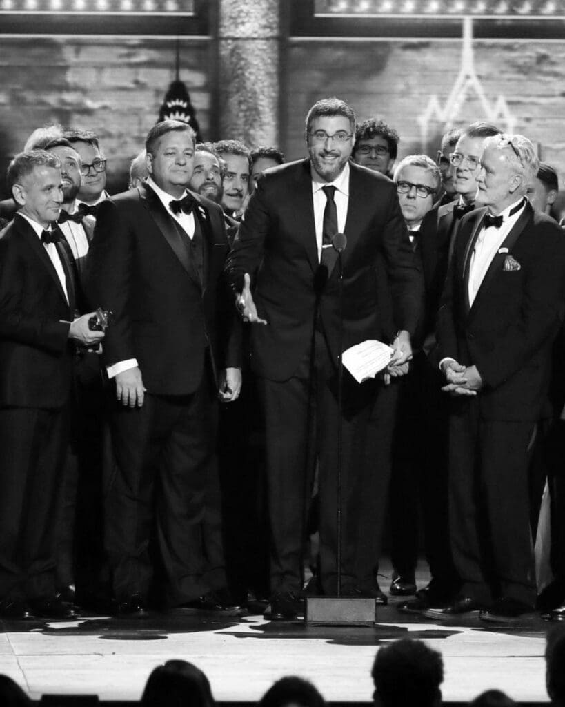 Group of men in tuxedos on stage at an awards show