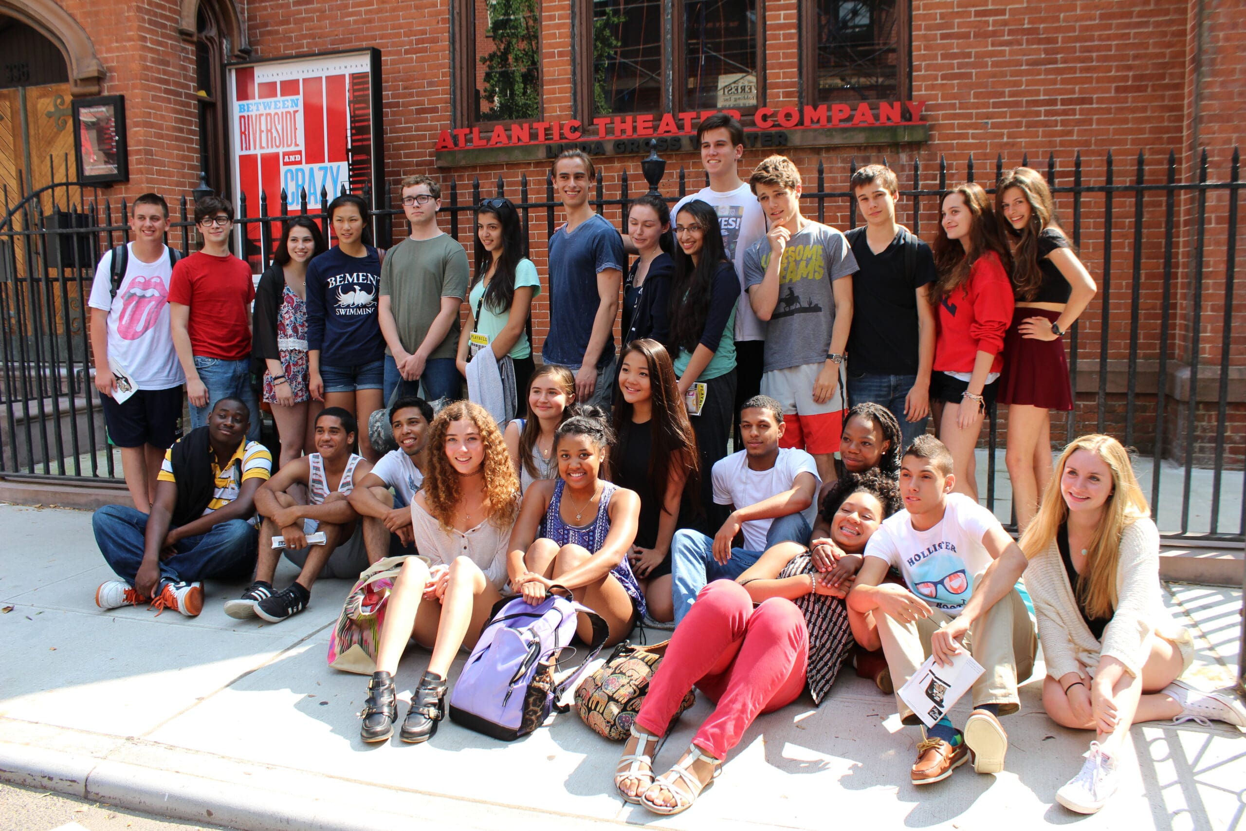 Group of young people posing outside the Atlantic Theater Company building.