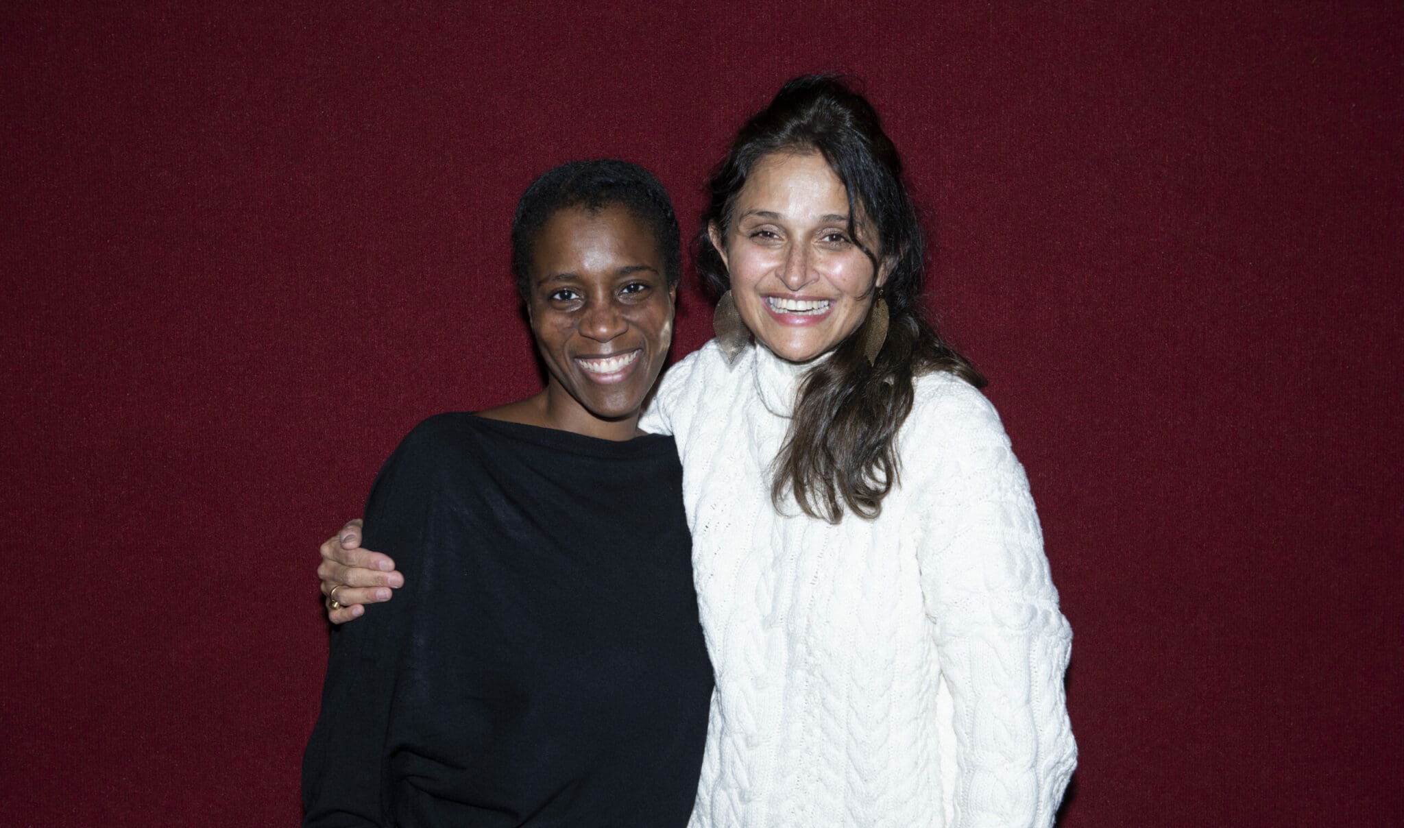 Two women smiling, arm around each other.