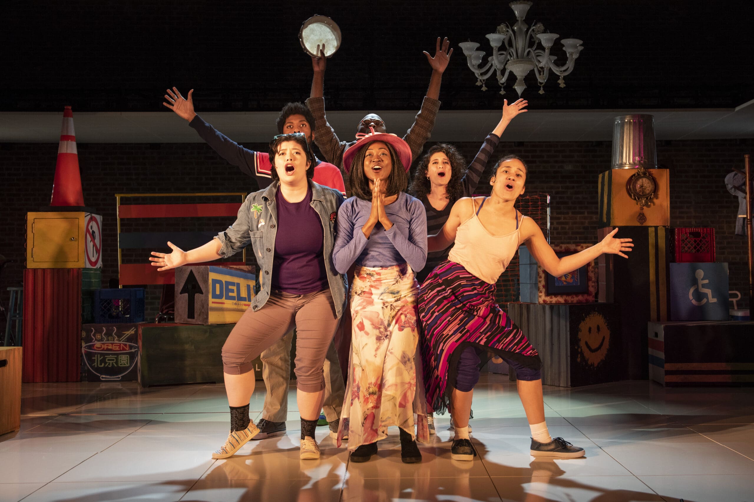 Ensemble cast performing on stage. Celebrating performance, theater, and acting with raised arms.