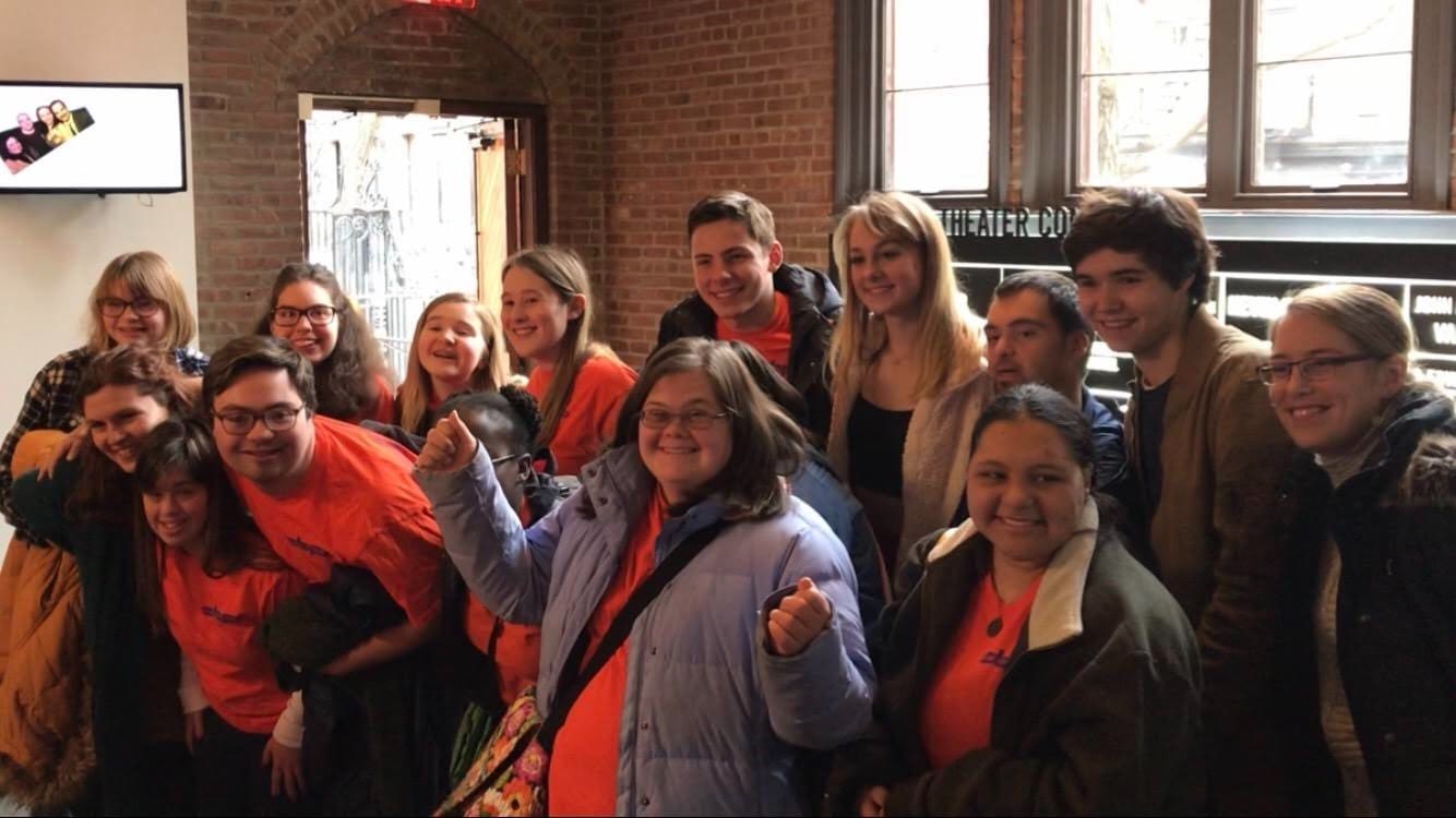 Group of diverse people smiling, likely involved in inclusive theater, representing community and performance.