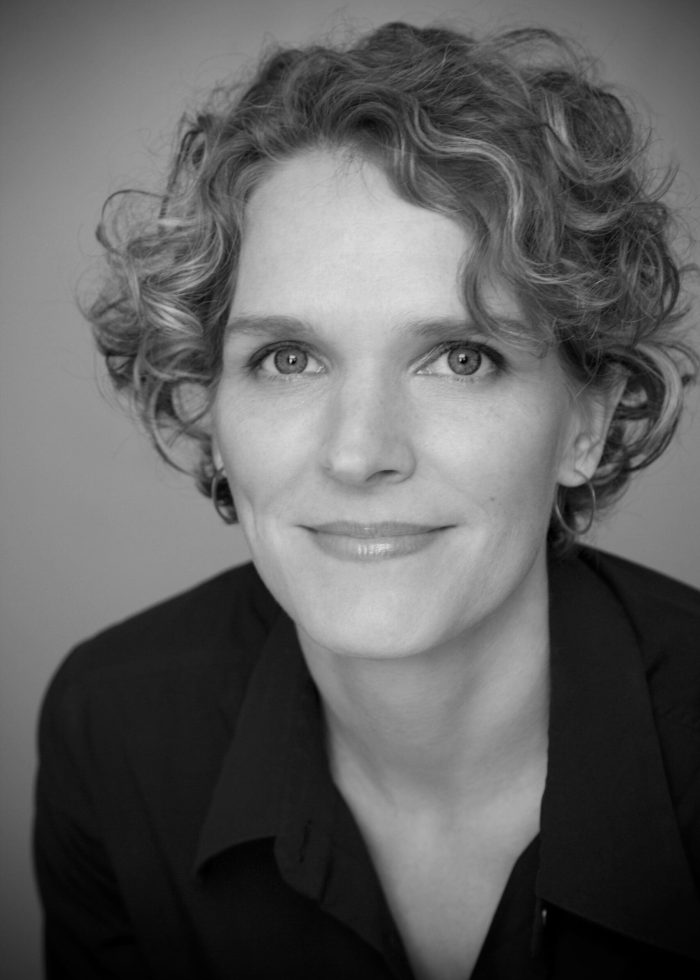 Melissa James Gibson, headshot, woman with curly hair smiling