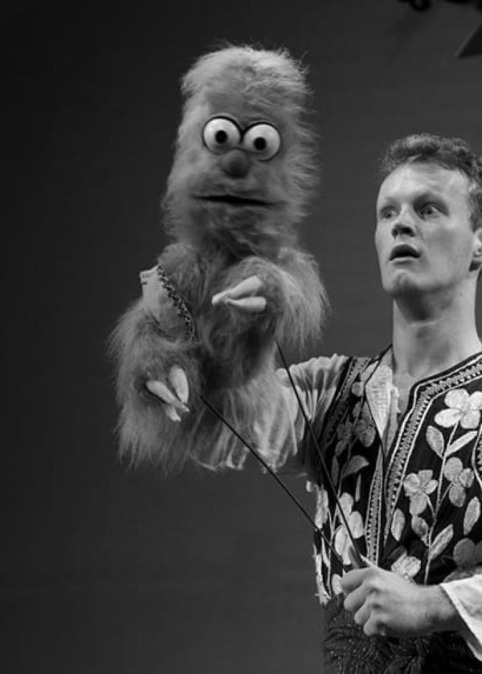 Man performing with puppet, likely from "1001 Nights: A Love Story About Loving Stories" play.