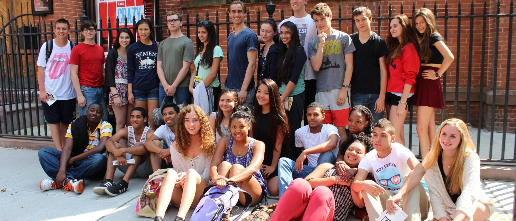 Group of young people posing outside the Atlantic Theater Company building.