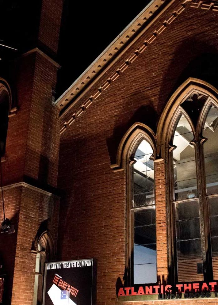 Atlantic Theater Company building at night, featuring its flag and illuminated signage.