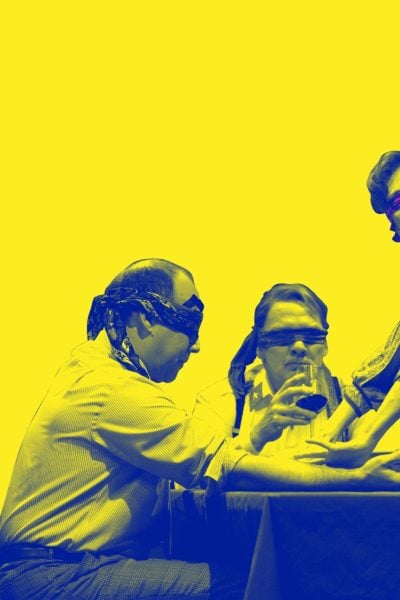 Blindfolded individuals at a table, a woman guides them. Mysterious night scene.