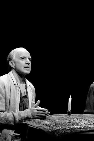 A man and woman sit at a table with lit candles, sharing a serious moment. Ghost stories.