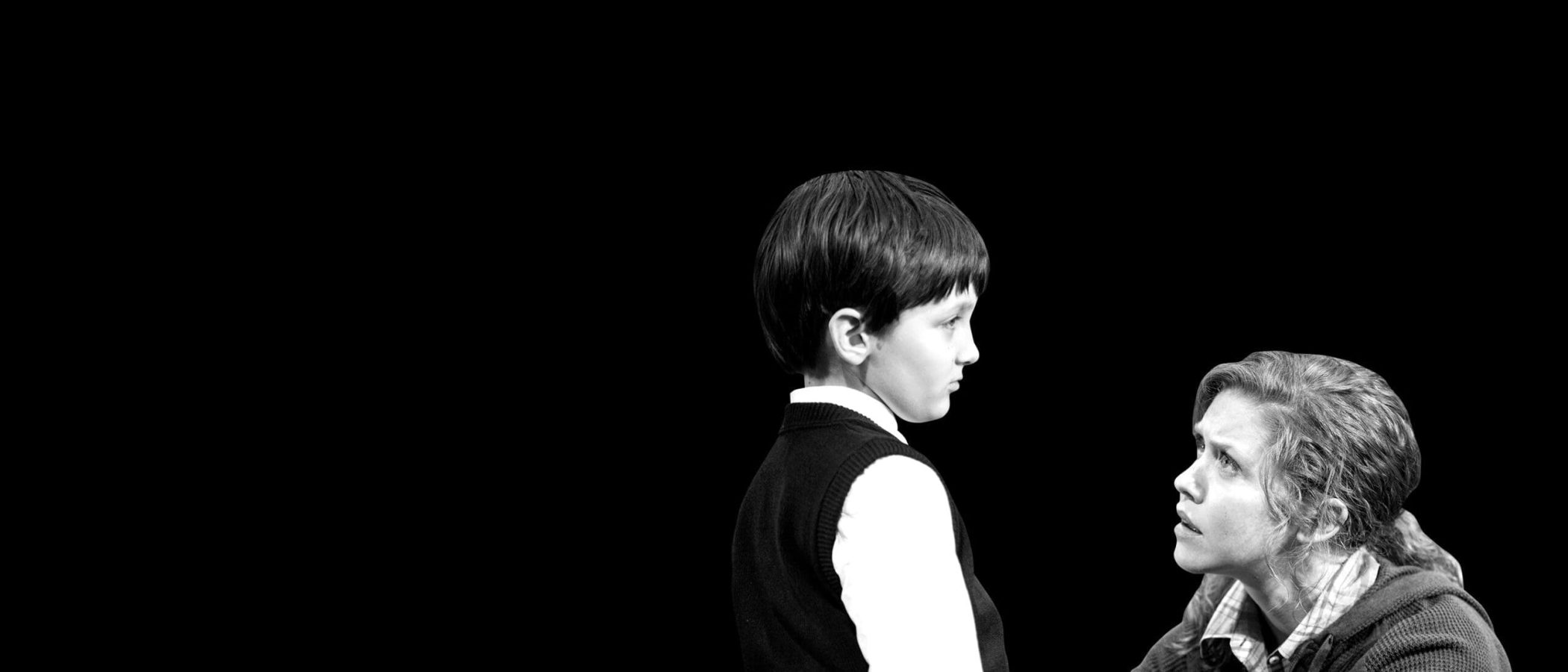 A woman and young boy face each other, the woman looking concerned.