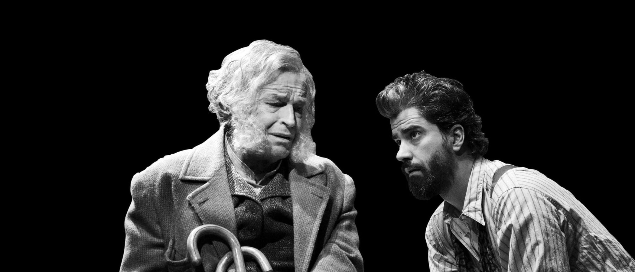 Black and white photo of two men, one elderly, one younger, in conversation. A scene of legacy and posterity.