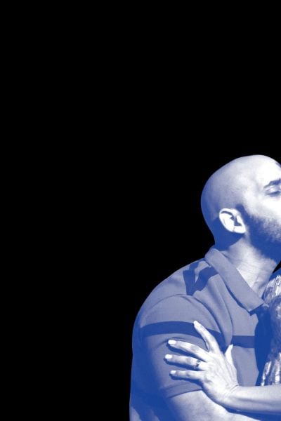 Close-up of a man kissing a woman's neck; she looks away.