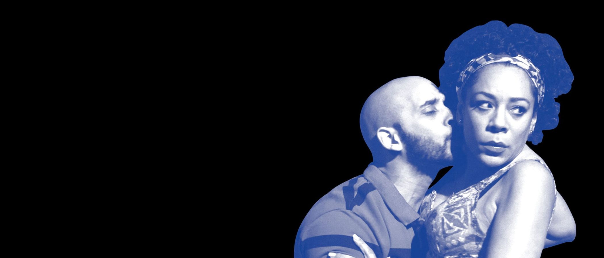 Close-up of a man kissing a woman's neck; she looks away.