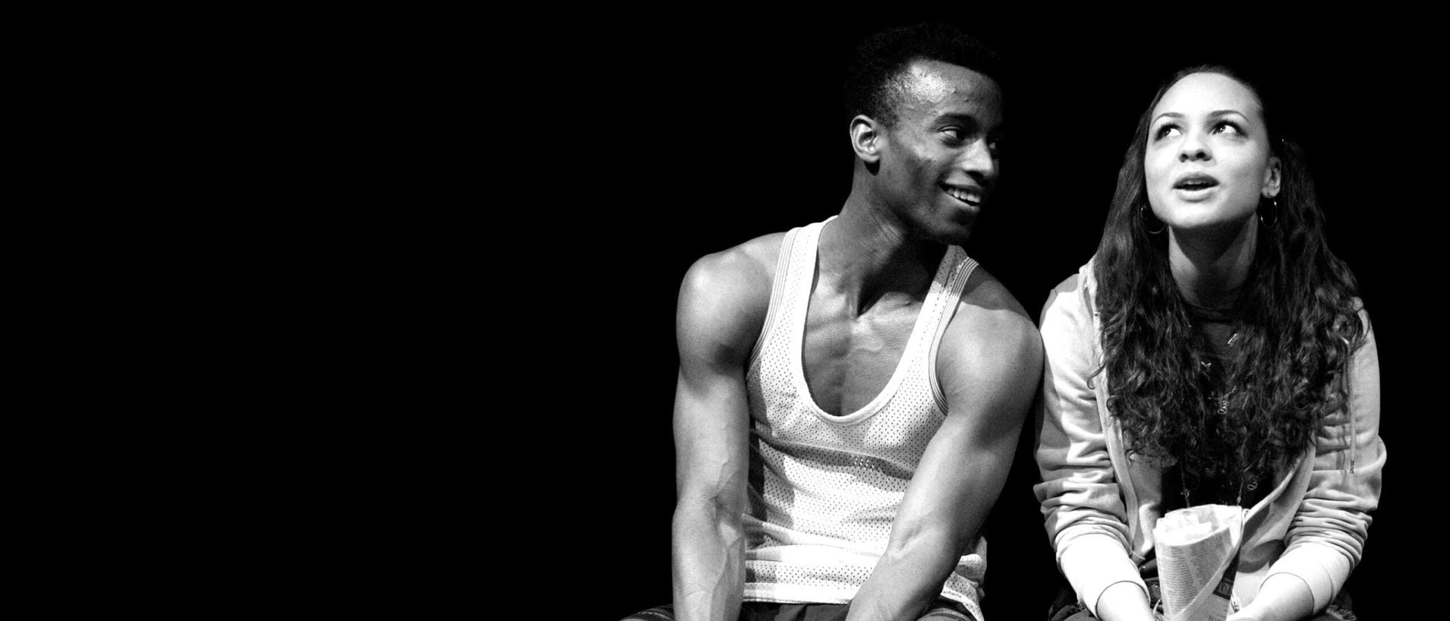 Man and woman sit, looking at each other, possibly reflecting the loneliness theme.