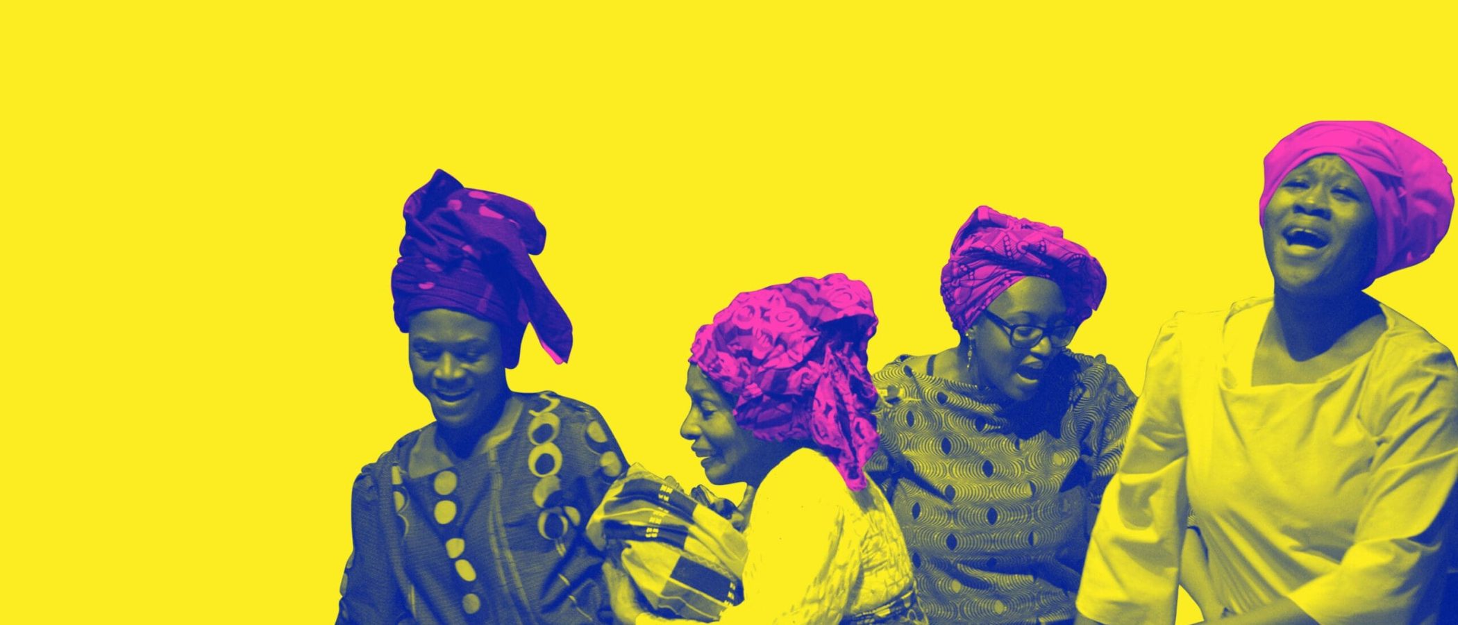 Four women in vibrant head wraps and patterned dresses joyfully celebrate.