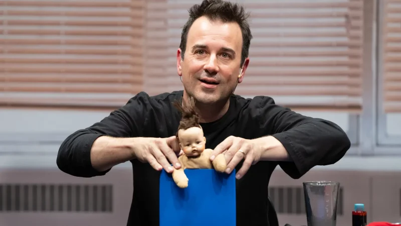 Magician performing a trick with a baby doll in a blue box. Originality in magic?