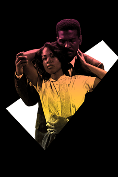 A couple embraces, woman in yellow, man in dark suit.