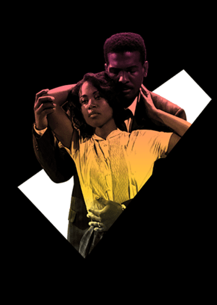 A couple embraces, woman in yellow, man in dark suit.