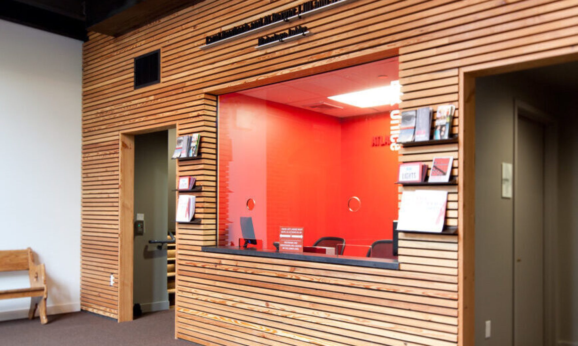 ATC-lobby Reception desk with wooden paneling and a red interior. Relaxed Performances signage above.