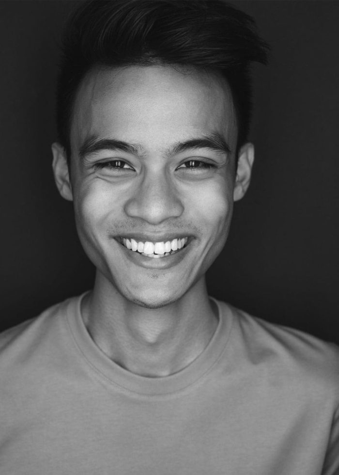 Aaron Banes smiling, close-up portrait in black and white