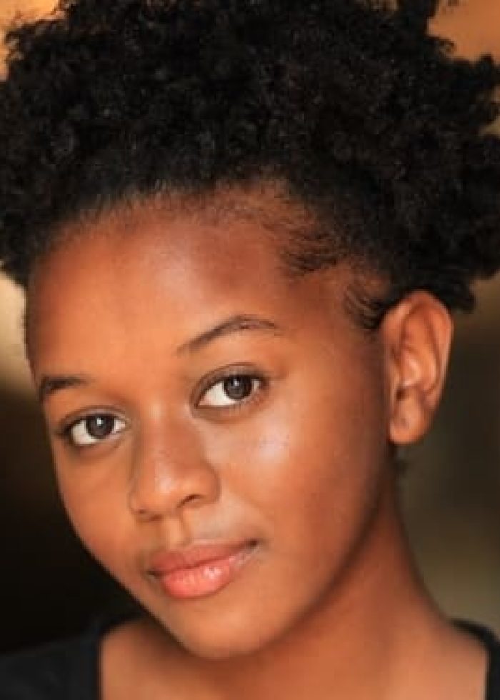 Alexis Kulani Woodard smiling, with short natural hair