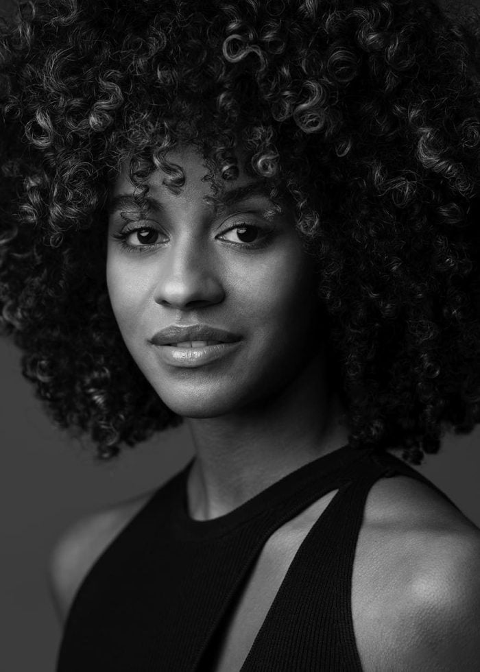 Angélica Beliard, portrait in black and white, curly hair, looking at the camera.