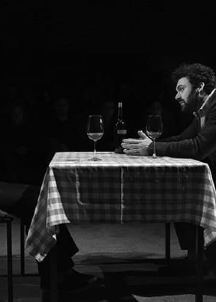 Man and woman at table in theatre performance of 'Animal'.