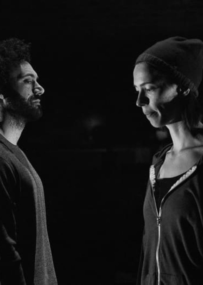 Two actors face each other in a scene from "Animal," theater review. Intense moment on stage.