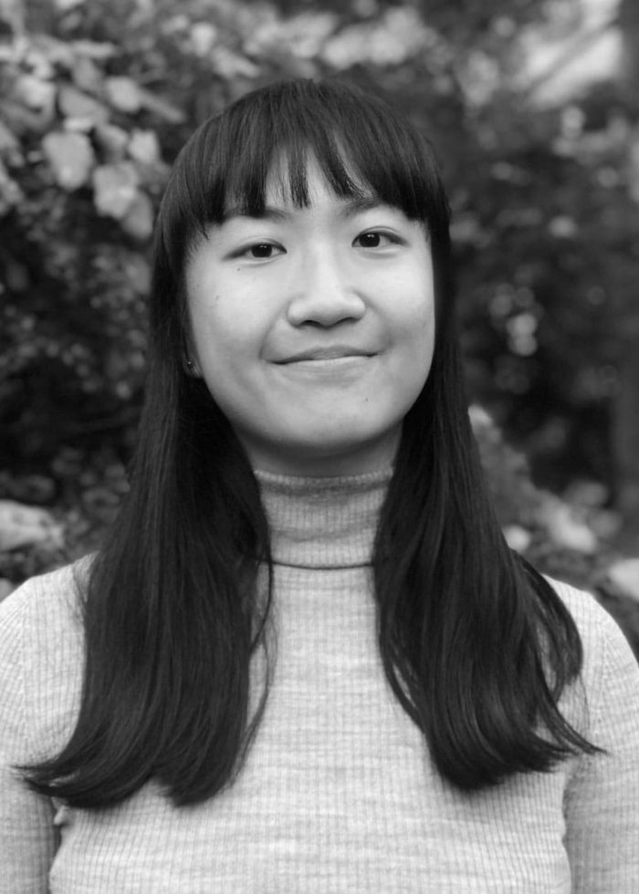 Annie Fang smiling, with long dark hair and bangs, wearing a grey turtleneck