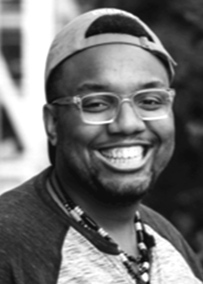 Smiling man wearing glasses, baseball cap, and necklace. Portrait.