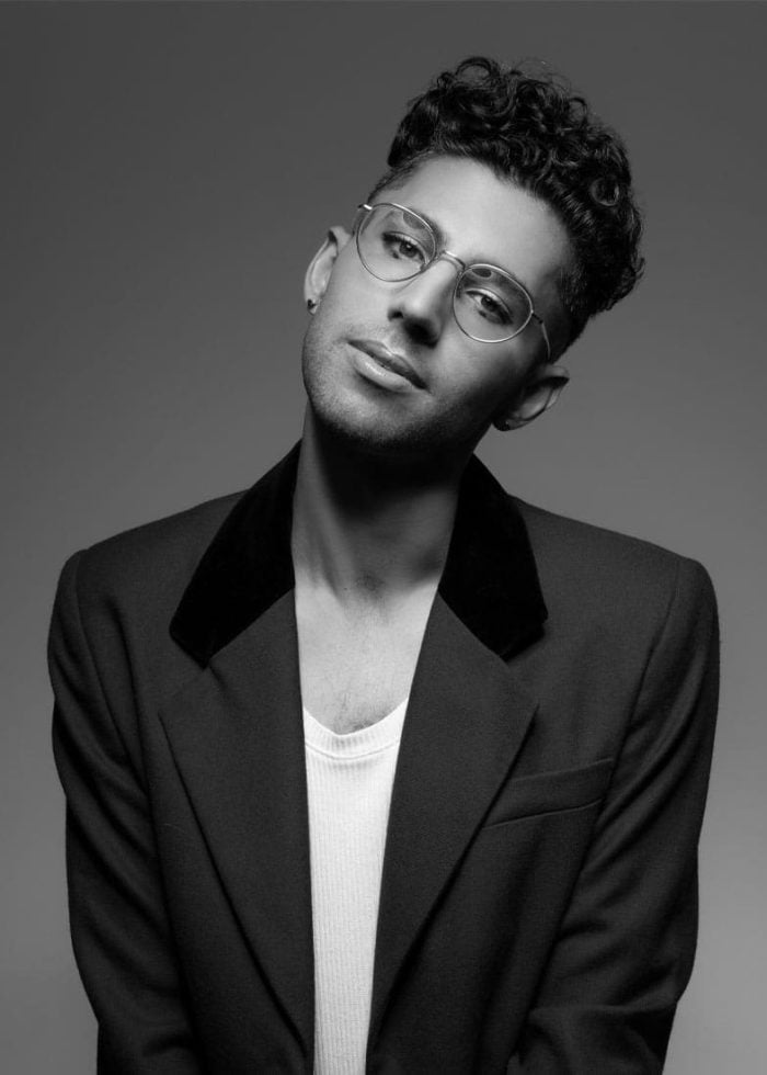 Asher Lloyd Ehrenberg wearing glasses and a blazer, looking at the camera