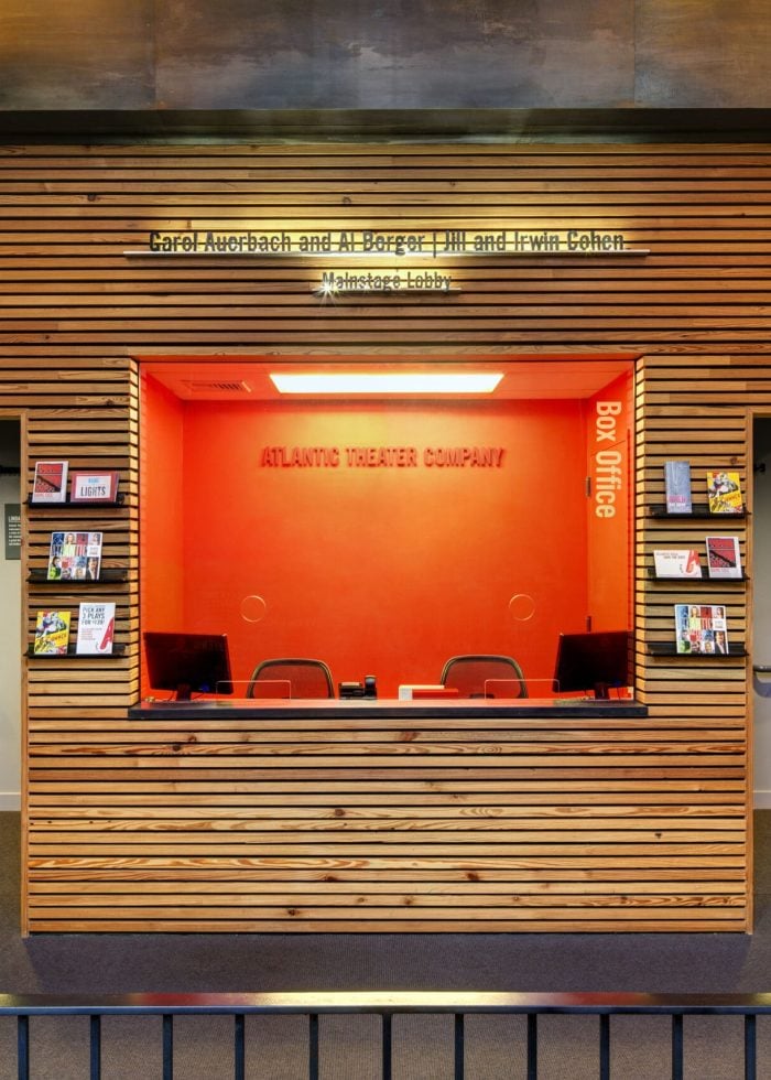 Atlantic Theater Company box office with orange accents and wooden paneling. Features "Box Office" signage.