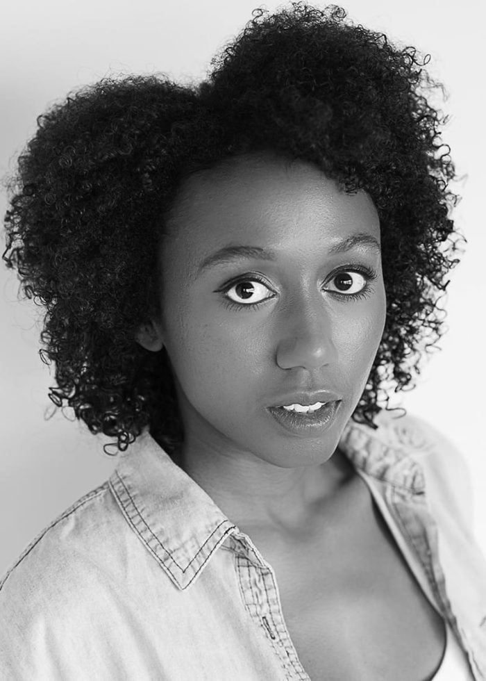 Portrait of Auberth Bercy with curly hair, wearing a denim shirt, gazing directly at the camera.