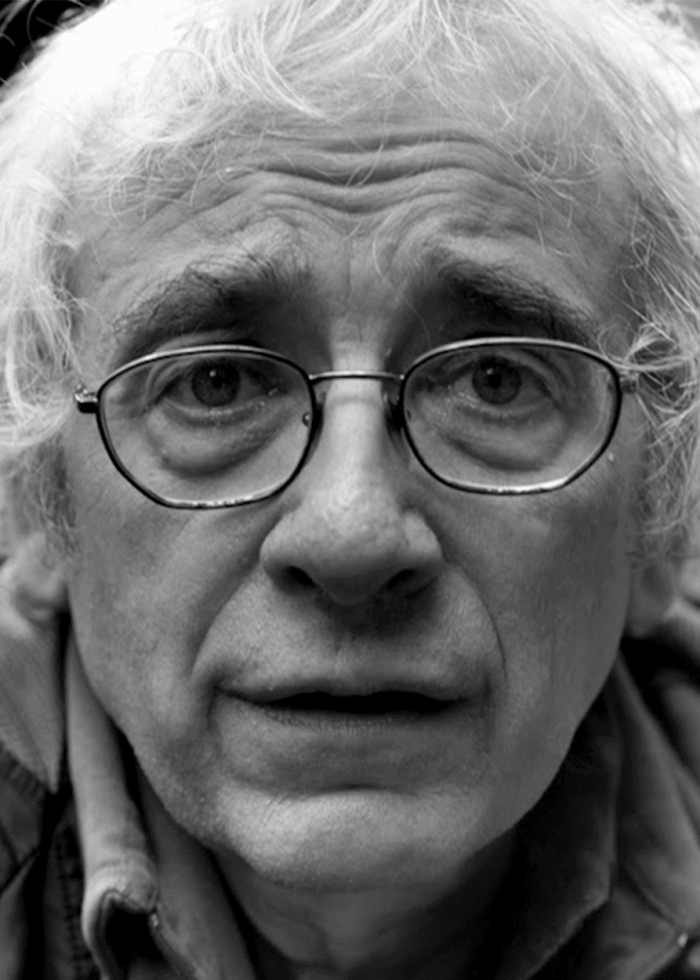Close-up of Austin Pendleton wearing glasses, looking directly at the viewer.