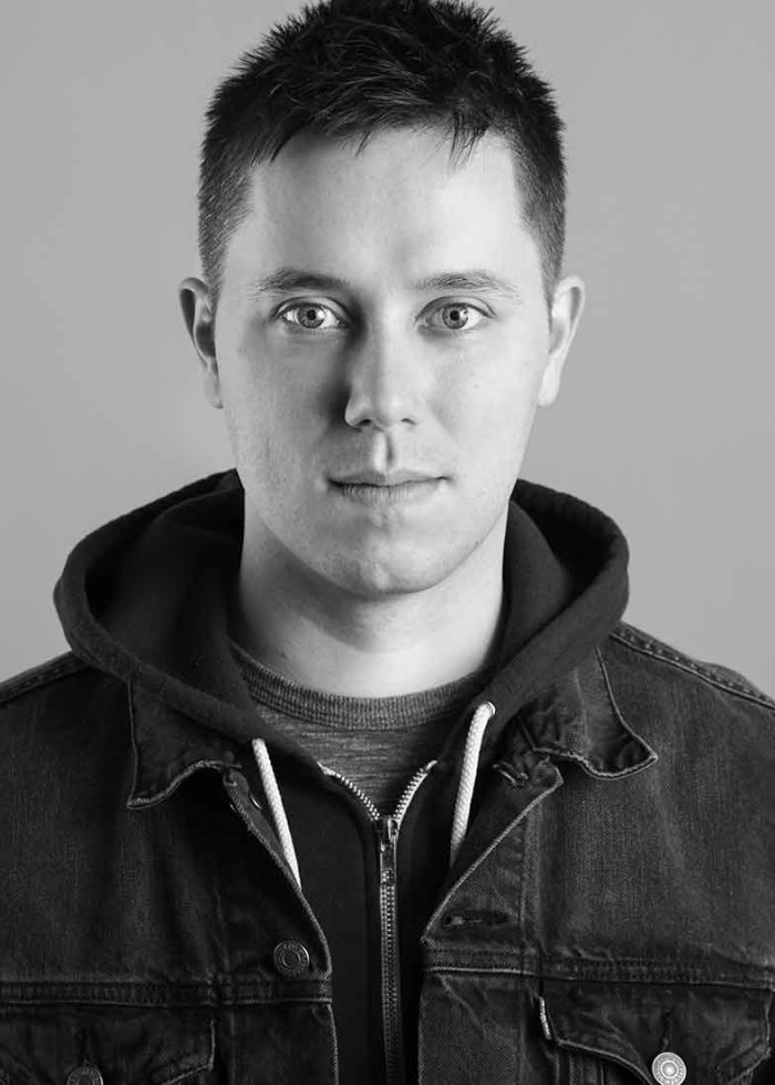 Austin Sanders in a denim jacket, looking directly at the camera.