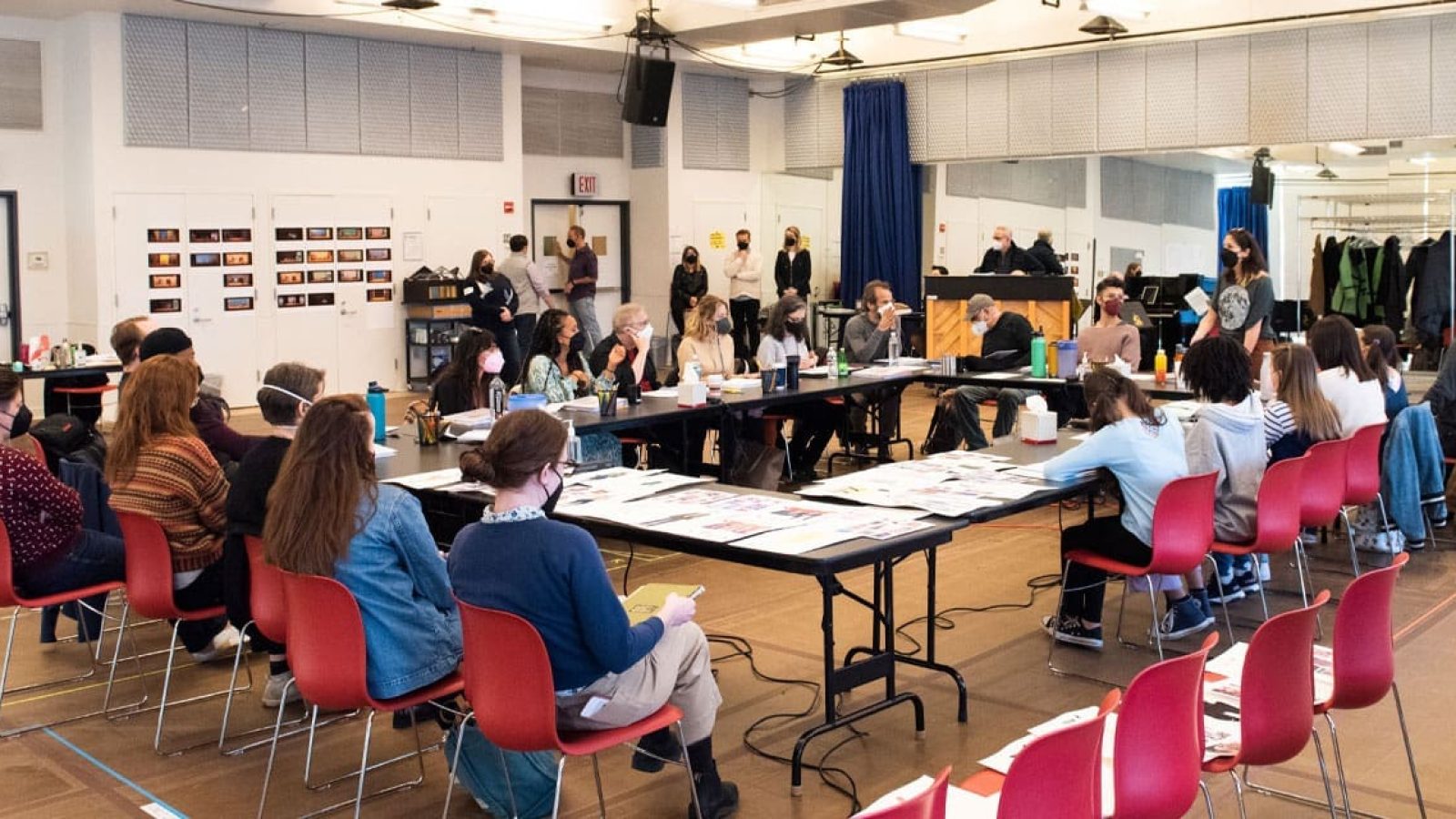 Actors and crew in a rehearsal room, working on a production.