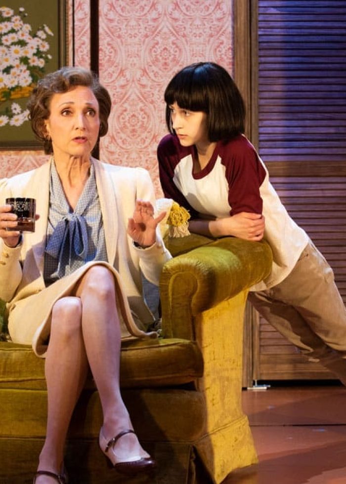 Sarah Silverman's "The Bedwetter" on stage: Actress seated with young actor leaning on chair.