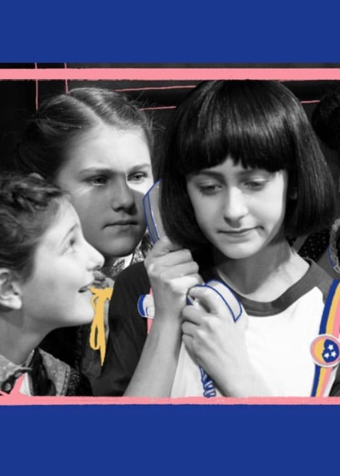 Cast of "The Bedwetter" play: young girls looking at each other, one holding a phone.