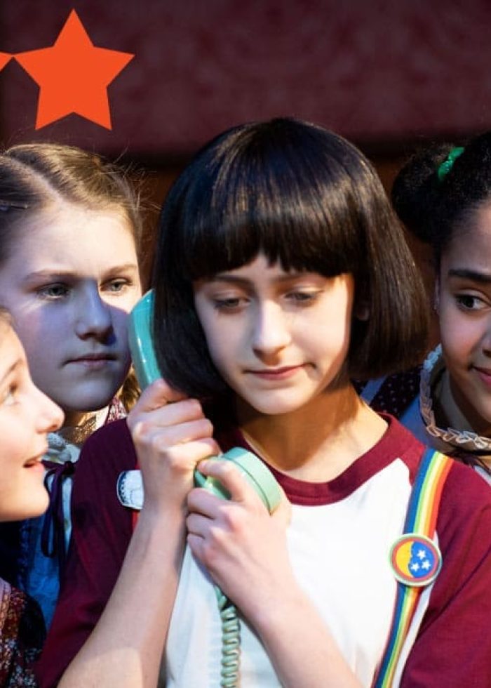 Four young actresses in a play, one holding a phone. Sarah Silverman musical review.