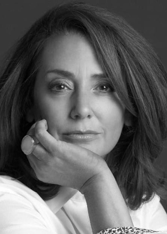 Talia Balsam looking at the camera, resting her chin on her hand.