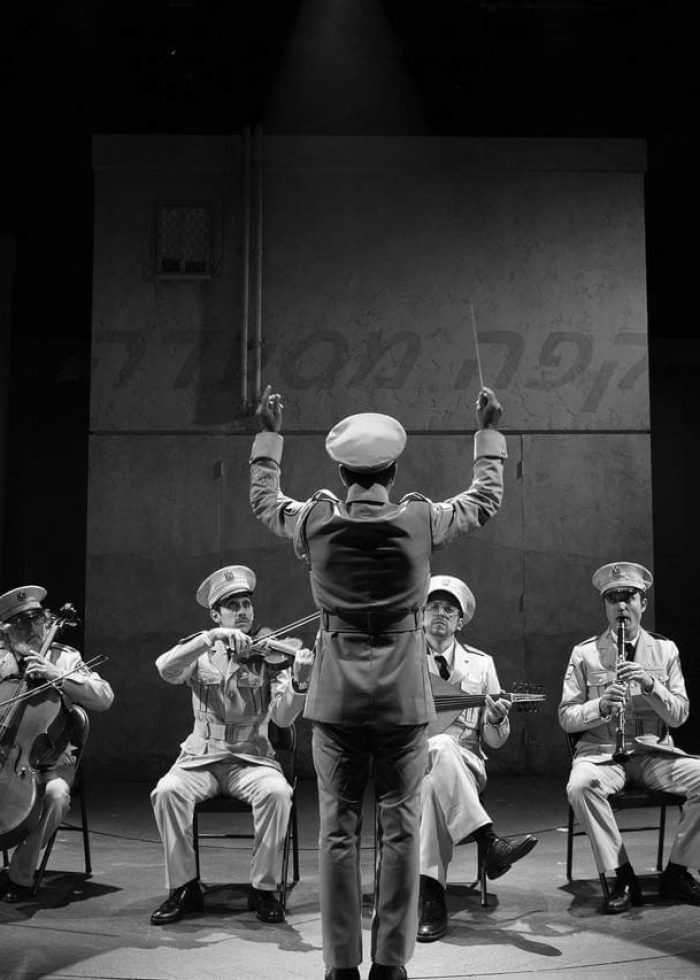 A black and white photo from "The Band's Visit" musical, showing the band in uniform with the conductor.