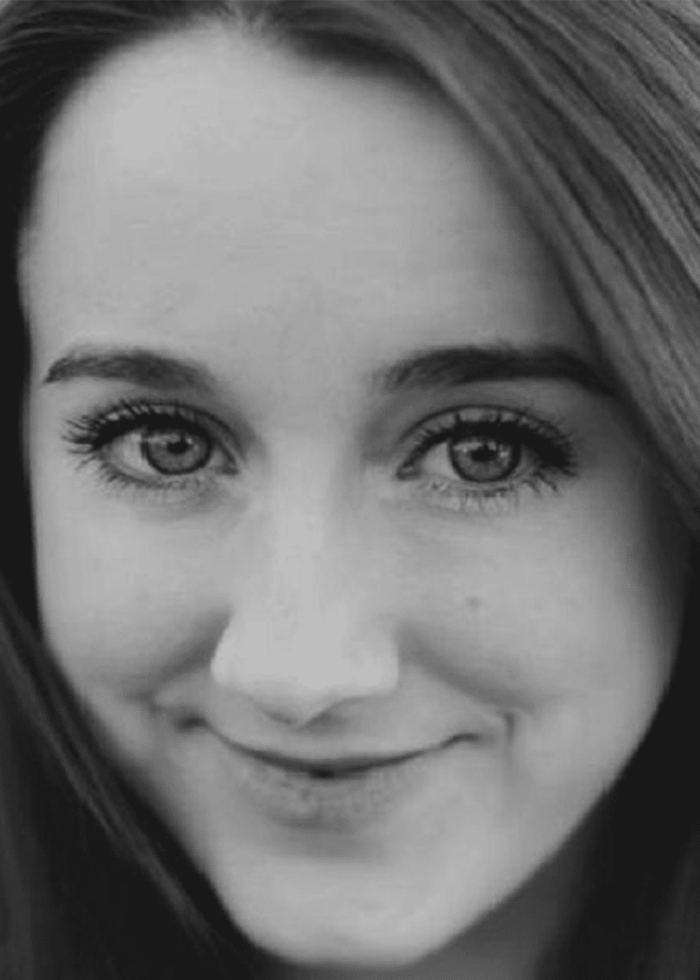 Close-up portrait of a smiling woman with dark hair and expressive eyes.