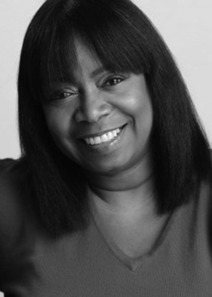 Benja Kay Thomas smiling, wearing a red shirt, looking at the camera