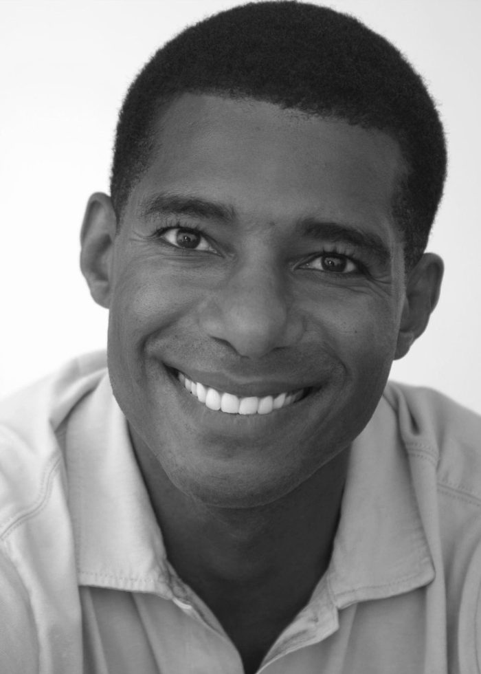 Close-up portrait of a smiling Black man with short hair