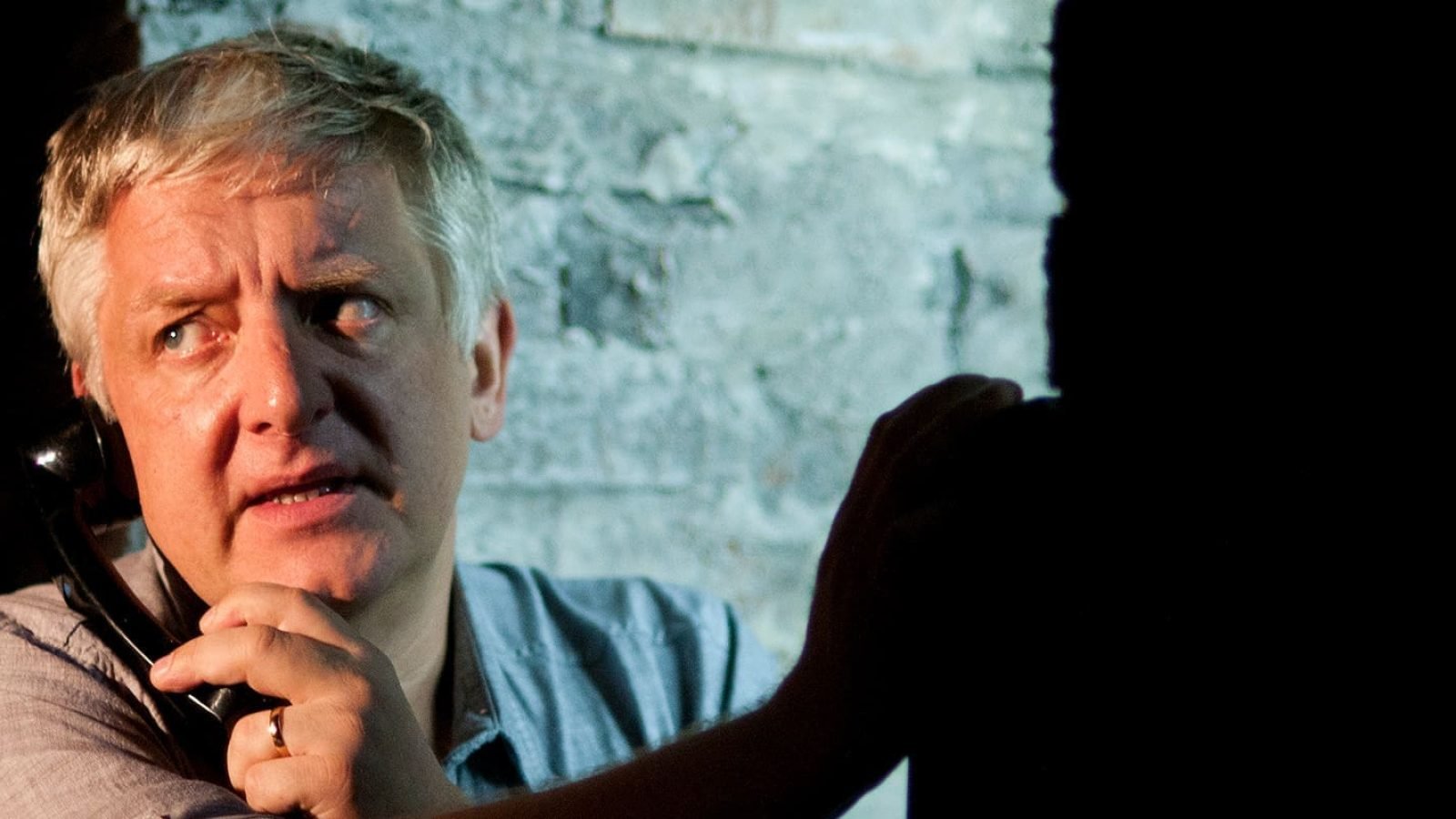 Man on phone, worried expression, looking over shoulder