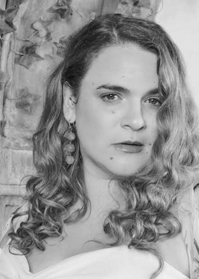 Bonnie Milligan in a black and white portrait with curly hair and earrings.