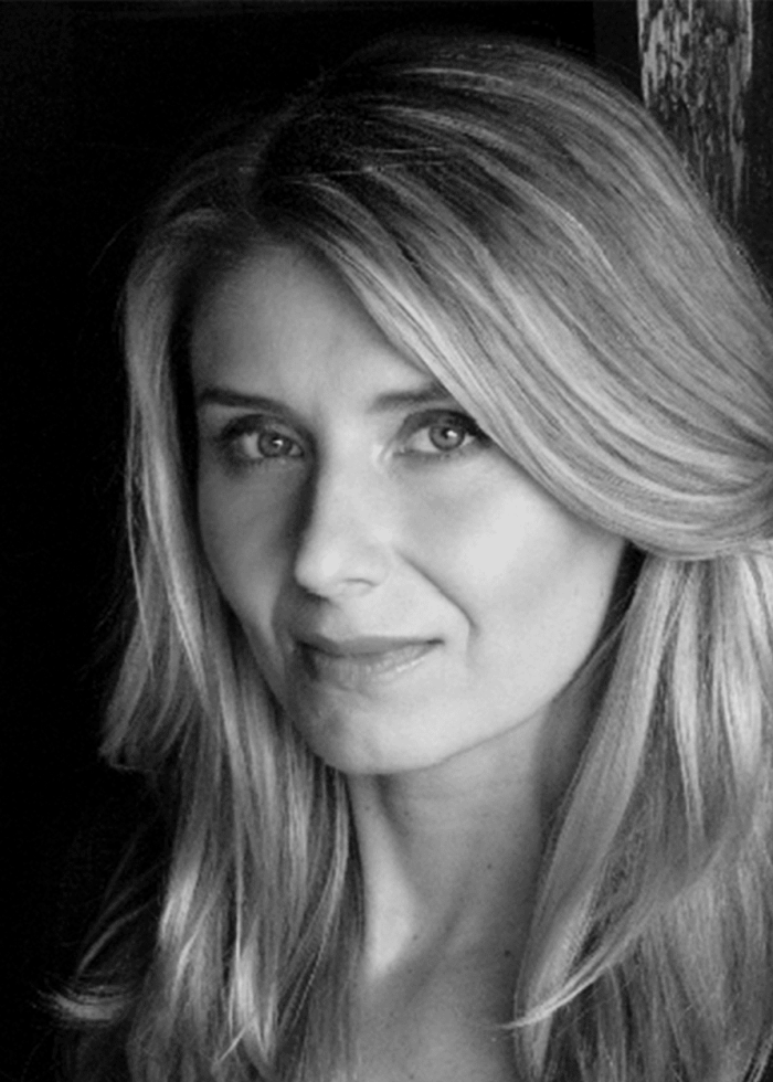 Portrait of Nadia Bowers, a woman with long blonde hair, looking at the camera.