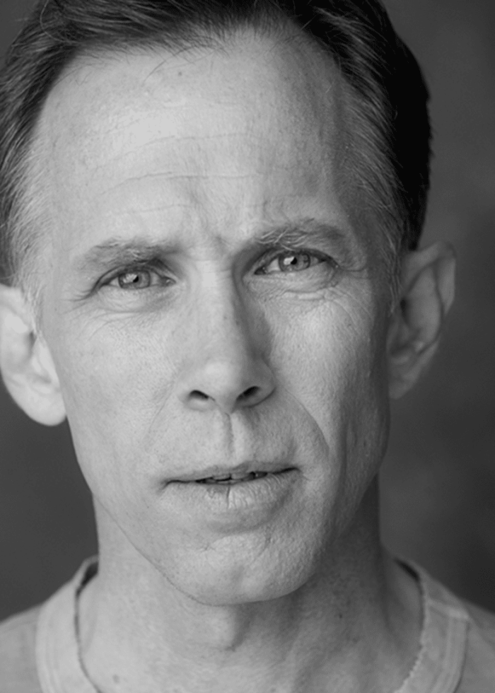 Black and white headshot of Bruce McKenzie, looking directly at the camera.