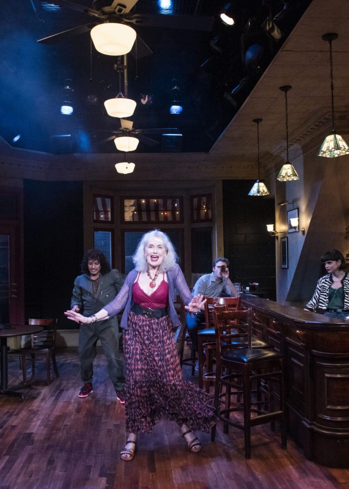 A lively scene in a Cornelia Street bar, featuring a woman singing and patrons seated at tables and the bar.