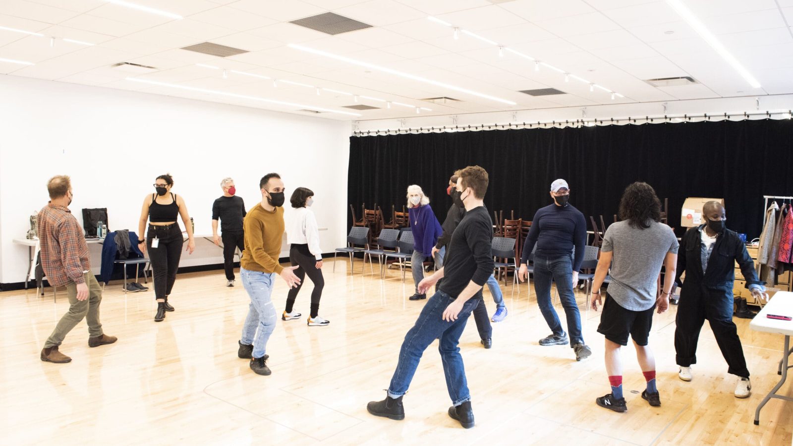 Actors wearing masks rehearse a scene in a studio.
