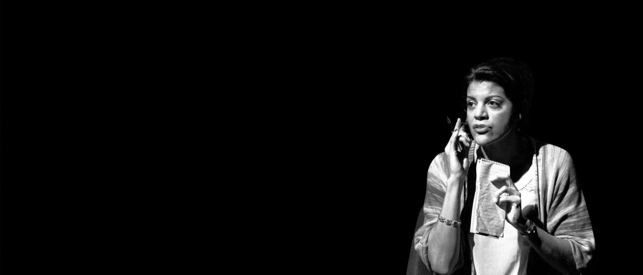 Woman on phone, taking notes, thoughtful expression.