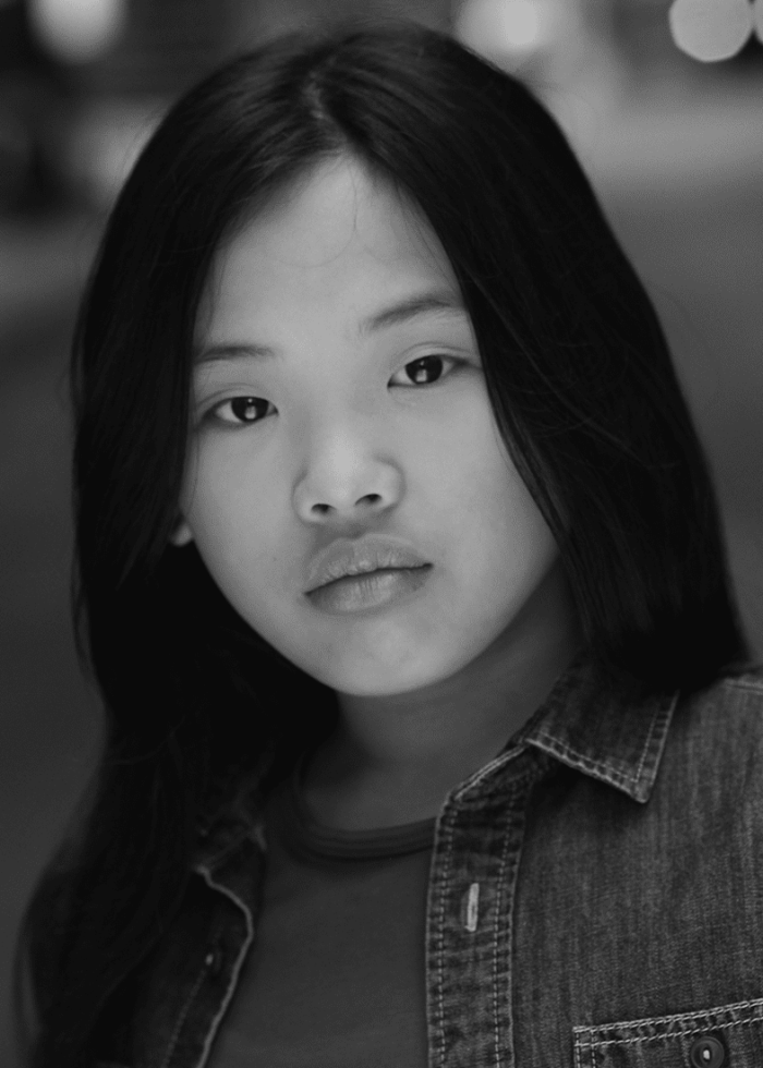 Portrait of a young girl with long black hair, wearing a denim shirt.